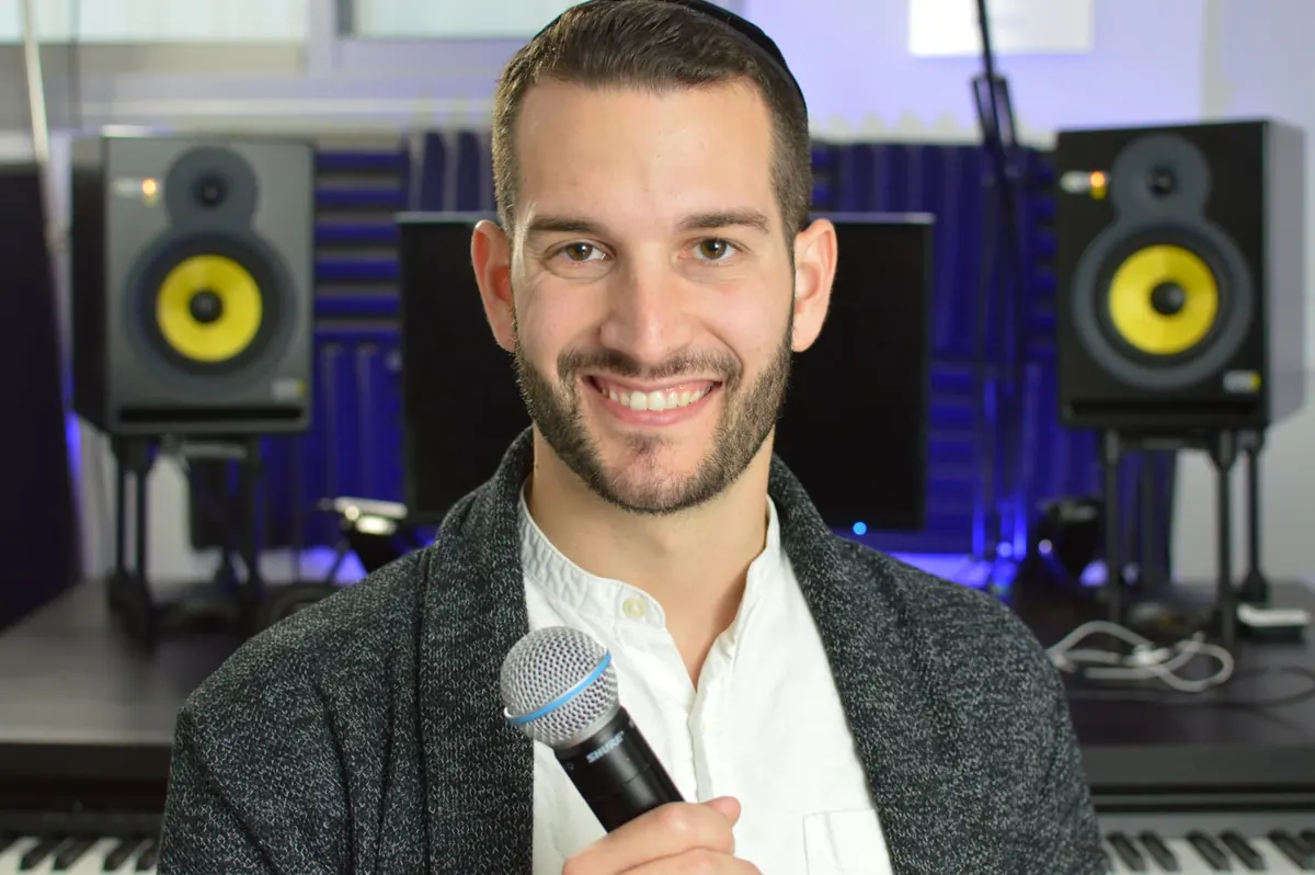 Adam Mishan, your vocal coach, holding a microphone in the studio